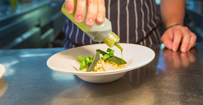 Chef prepping risotto dish on the pass